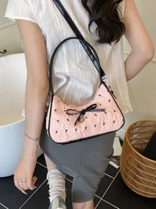 Stylish pink crescent shoulder bag for women featuring a black bow and 'K' print.