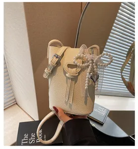 Close-up of cream lychee texture cell phone bag with pearl bow and heart charm