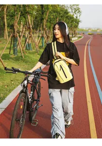 Lifestyle shot of a yellow nylon chest bag worn by a model during outdoor cycling activities