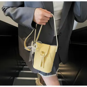 Detailed view of yellow litchi grain bucket bag with elegant bow and pearl charm ornament.
