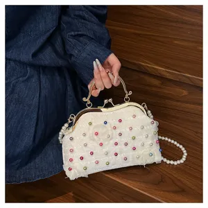Dettaglio di borsa da sera bianca con perline colorate e manico in metallo dorato
