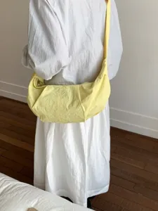 Minimalistische hellgelbe Sichel-Schultertasche aus Nylon am Modell getragen