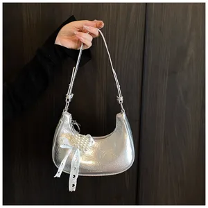 Silberne Ölhaut-Hobo-Tasche mit Perlbogendetail, in der Hand eines Models präsentiert