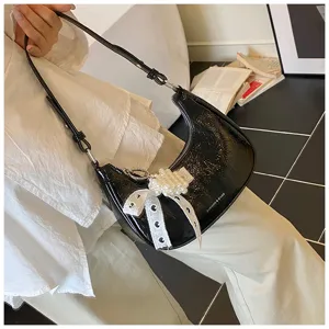 Elegante Nahaufnahme einer schwarzen Lackleder-Hobo-Tasche mit Perlen-Spitzenbogen-Detail