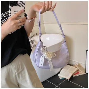 Detailaufnahme einer lavendelfarbenen Schultertasche aus Ölleder mit Perlenanhänger.