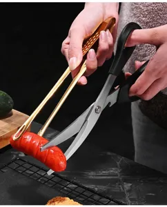 Gros plan d'une pince dorée et de ciseaux de cuisine coupant une saucisse grillée.