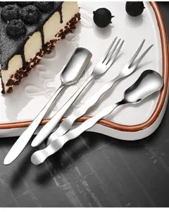 Macro view of creative wave-shaped stainless steel dessert spoon and fork set on a plate