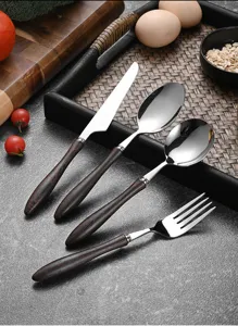 Detail view of vintage cutlery set with dark wenge wood handles and polished steel.