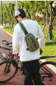 Male model wearing an olive green nylon sling bag while standing with a bicycle outdoors