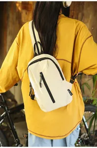 Detail view of a white nylon outdoor cycling sling bag worn by a model in a casual setting