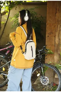 Compact beige nylon outdoor cycling sling bag worn by a model in a garden setting