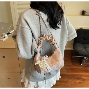Vue détaillée d'un sac hobo rose plissé élégant avec un pendentif nœud en perles.