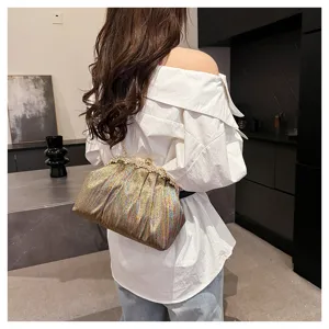 Détail d'un sac de soirée tissé coloré scintillant avec fermoir en strass porté par un modèle
