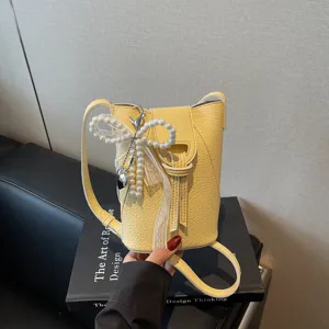 Elegant yellow lychee leather mini bucket bag featuring a decorative pearl bow-knot