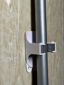 Primo piano di un porta mocio grigio a parete che blocca saldamente un palo metallico