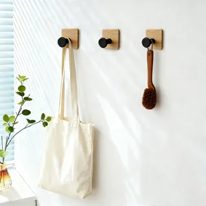 Primo piano di ganci da parete moderni con base in legno e finitura nera nella stanza.
