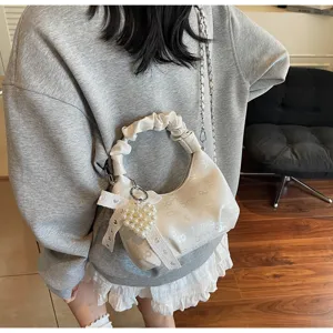 Vue détaillée du sac dumpling plissé blanc avec breloque cœur en perles et nœud