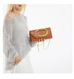 Elegante Detailansicht der braunen Clutch mit goldenem Ring und feiner Kettenriemen