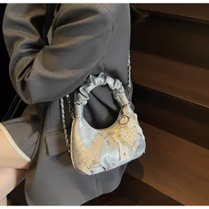 Détail du sac hobo argenté avec breloque cœur en perles et ruban à nœud élégant