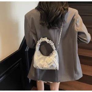 Sac à main argenté avec poignée froncée et breloque perle en cœur sur un mannequin