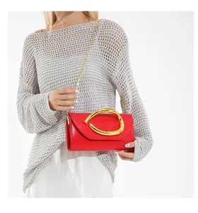 Schicke rote Abend-Clutch mit goldener Kette, getragen von einem Modell im grauen Strickpullover.