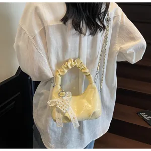 Détail du sac à main plissé jaune clair avec charme cœur en perles et nœud en dentelle