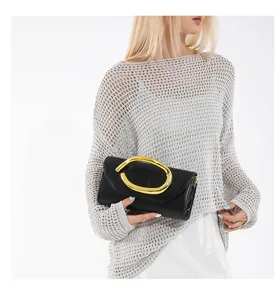 Elegante schwarze Abendtasche mit auffälligen Goldbeschlägen, gehalten von einem Modemodell