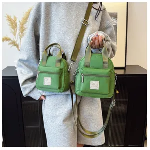 Zwei grüne Nylon-Handytaschen in verschiedenen Größen von einer Person in Grau getragen