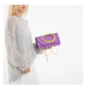 Detailansicht einer lila Abendtasche mit auffälliger goldener Hardware und Kette