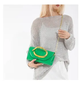 Stilvolle grüne Abend-Clutch mit goldenem Griff und Kettenriemen am Model getragen