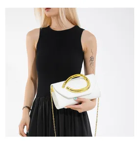 Detailansicht einer weißen Abend-Clutch mit einem markanten goldenen runden Metallgriff.