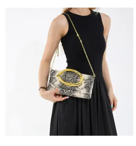 Elegante Abendtasche mit Schlangenmuster und goldener Kette am Modell präsentiert