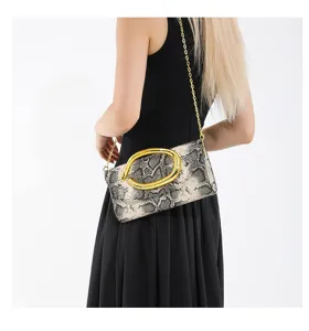 Modell mit einer Umhängetasche aus Schlangenleder mit markanter goldener Metallschnalle.