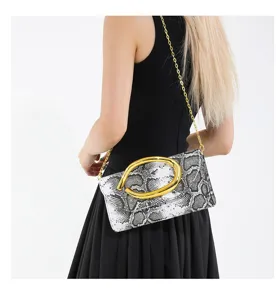 Elegante Abend-Clutch mit Schlangenmuster und goldener Kette am Model präsentiert