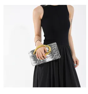 Detailansicht einer stilvollen Clutch mit Schlangenmuster und goldenem Metallgriff.