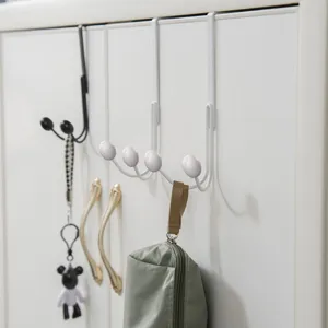 Dettaglio del gancio da porta in metallo bianco montato e fissato su un'anta d'armadio.
