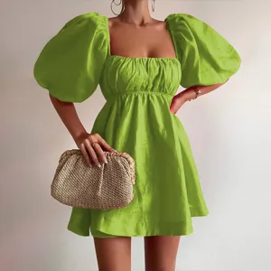 Green square neck puff sleeve mini dress detail view with woven straw clutch bag matching.