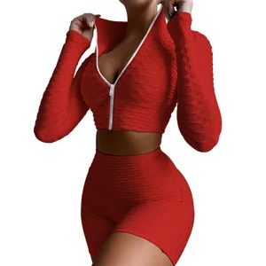 Women red textured activewear set, long sleeve zip crop top and high waist shorts detail.