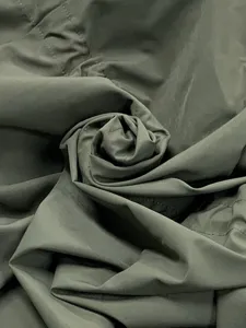 Close-up detail of military green trench coat fabric, showing fine texture and neat stitching.