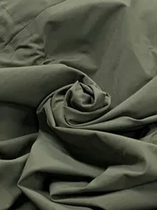 Close-up detail view of solid color trench coat fabric, showing soft fabric texture.