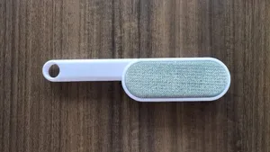 Close-up detail of the double-sided lint remover brush fabric head and white plastic handle.