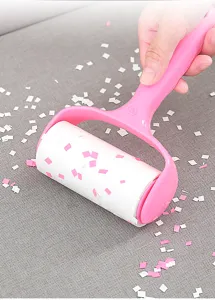 Detail shot of a pink plastic lint roller efficiently removing debris from fabric.