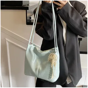 Close-up detail of a light blue textured underarm tote bag with a pearl pendant charm