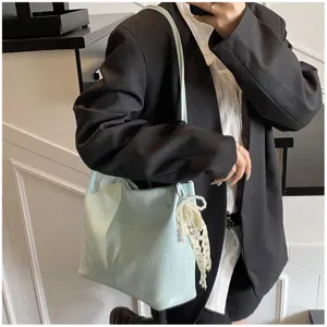 Fashionable mint green underarm tote bag featuring crinkled texture and decorative pearl charm
