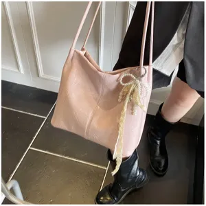 Detailed view of a pink textured faux leather tote bag featuring a pearl and lace charm