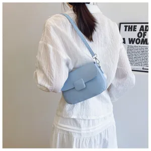Detailed view of a light blue textured flap shoulder bag on a model