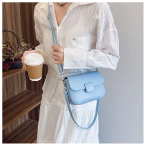 Detail view of light blue textured crossbody bag with flap and slim strap