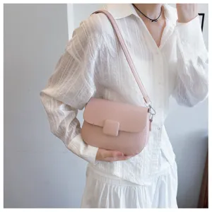 Close-up view of a stylish pink textured crossbody bag worn by a model in a white shirt
