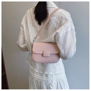 Detailed back view of a light pink textured crossbody bag worn on the shoulder