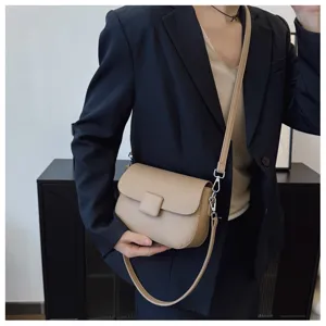 Detailed view of a chic beige textured flap crossbody bag styled with a navy blazer.